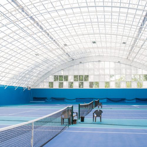 Wide angle shot of modern indoor tennis court interior in blue colors, copy space
