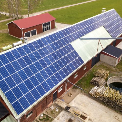 Top view of blue solar photo voltaic panels system on wooden building, barn or house roof. Renewable ecological green energy production concept.